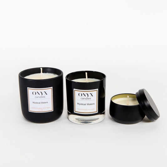 Pictured left to right, 12 oz matte black ceramic jar, 9 oz black glass jar, and 4 oz matte black tin candle variants for Onyx candles scent Mystical Waters