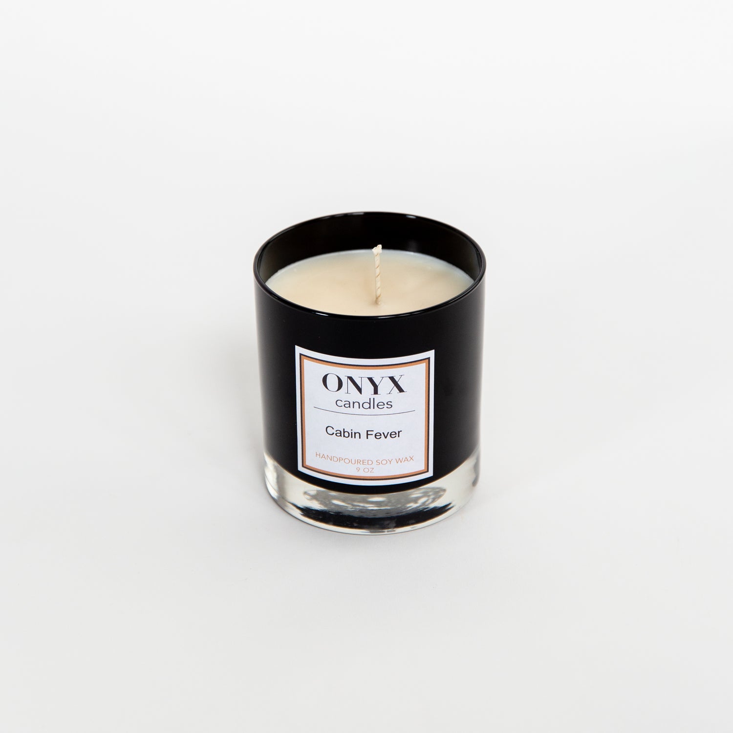 9 oz black glass candle in the scent of Cabin Fever